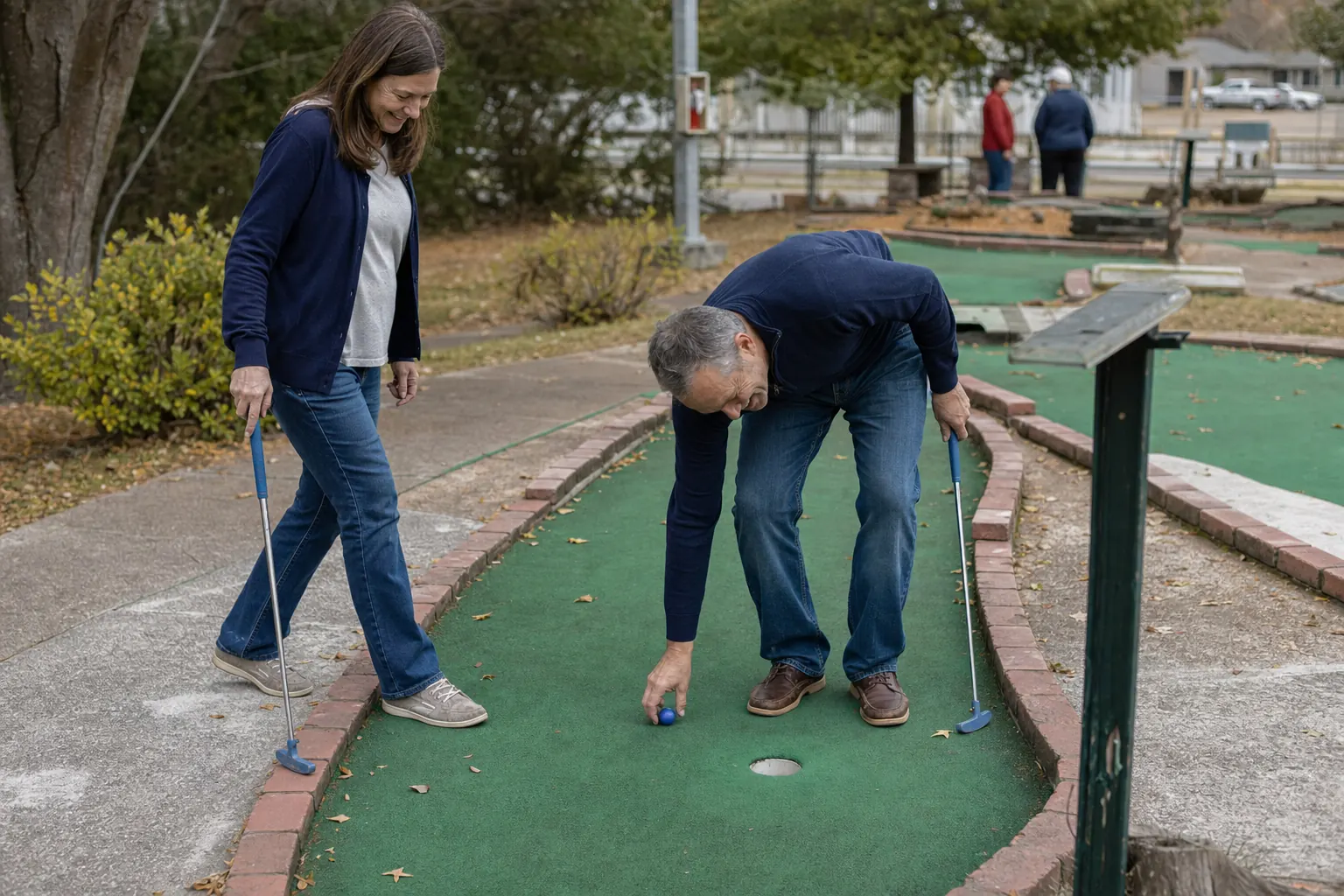 A couple over 40 enjoying a relaxed first date at a neighborhood miniature golf course